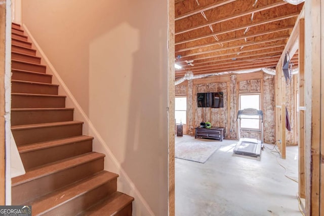 staircase featuring unfinished concrete floors