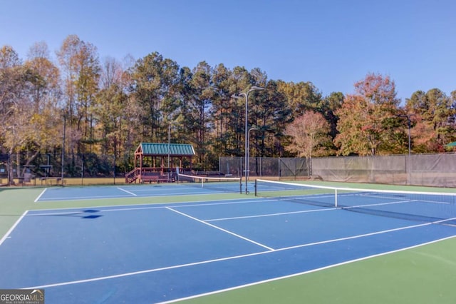 view of tennis court with community basketball court and fence