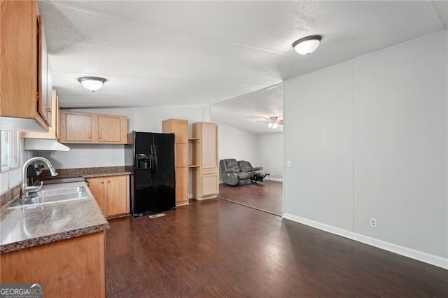 kitchen with dark wood finished floors, lofted ceiling, a sink, ceiling fan, and black fridge