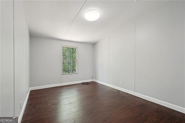 unfurnished room featuring dark wood finished floors, baseboards, and visible vents