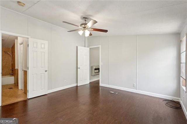 unfurnished bedroom featuring baseboards, heating unit, wood finished floors, and ceiling fan
