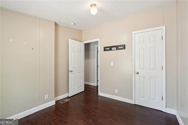 unfurnished bedroom featuring baseboards, wood finished floors, and visible vents