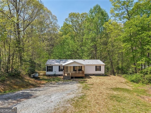 manufactured / mobile home featuring a forest view, crawl space, driveway, and covered porch