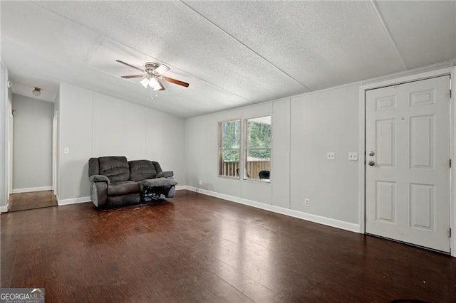 sitting room featuring baseboards, a ceiling fan, dark wood-type flooring, and a textured ceiling