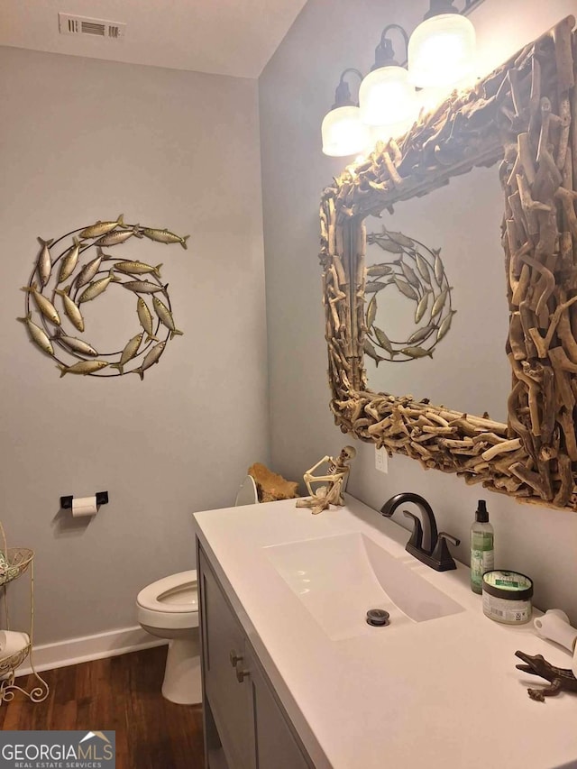 471 Getaway Ln, Baxley, GA 31513 - half bathroom featuring toilet, vanity, wood finished floors, and baseboards