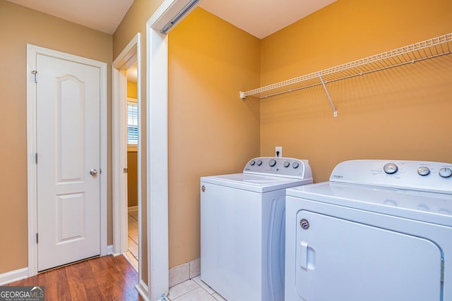laundry room featuring baseboards, wood finished floors, separate washer and dryer, and laundry area