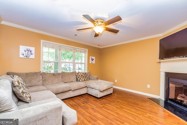 living room featuring wood finished floors, ceiling fan, and crown molding