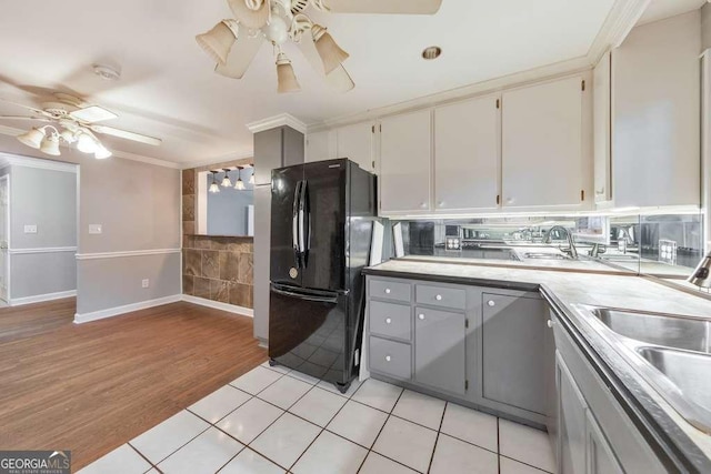 kitchen featuring freestanding refrigerator, ceiling fan, ornamental molding, light countertops, and light wood-type flooring