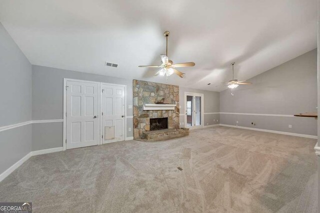unfurnished living room with a ceiling fan, lofted ceiling, carpet, baseboards, and a stone fireplace