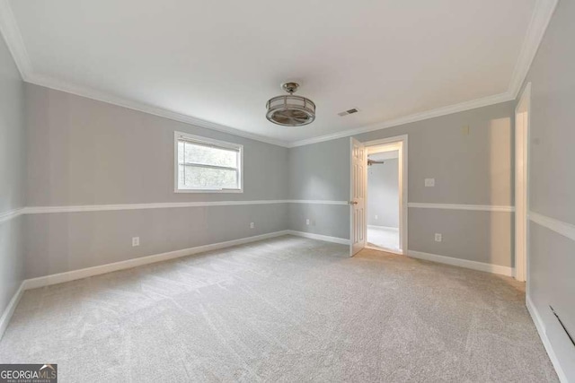 carpeted spare room featuring crown molding and baseboards