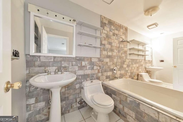 full bathroom featuring toilet, tile patterned floors, tiled shower / bath combo, tile walls, and a sink