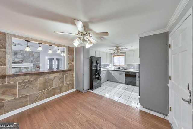 kitchen featuring black appliances, a ceiling fan, crown molding, light wood-style floors, and pendant lighting