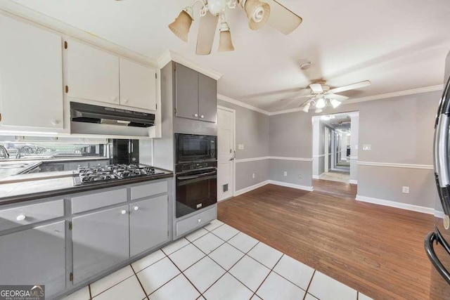 kitchen featuring a ceiling fan, black appliances, under cabinet range hood, crown molding, and light tile patterned floors
