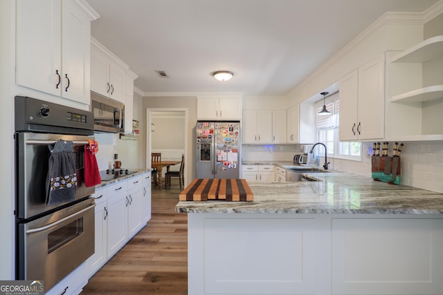 kitchen featuring white cabinets, open shelves, a sink, a peninsula, and appliances with stainless steel finishes