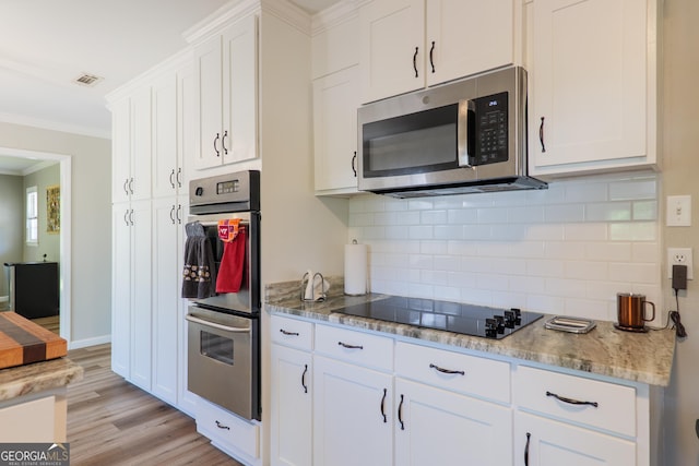 kitchen with tasteful backsplash, visible vents, white cabinetry, appliances with stainless steel finishes, and ornamental molding