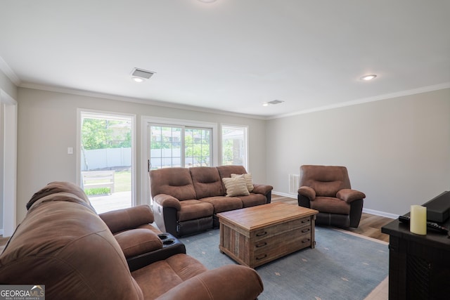 living room featuring visible vents, baseboards, wood finished floors, and ornamental molding