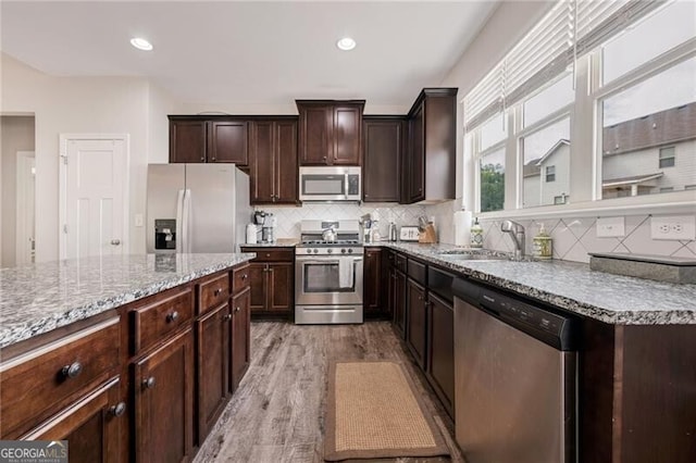 1129 Abundance Dr, Locust Grove, GA 30248 - kitchen featuring stainless steel appliances, a sink, dark brown cabinetry, backsplash, and light stone countertops