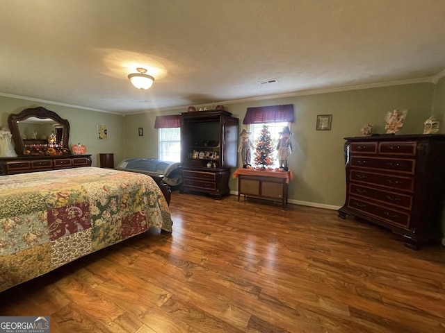 bedroom with crown molding, wood finished floors, and visible vents