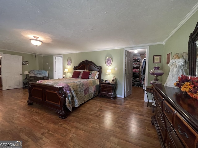 bedroom featuring a walk in closet, ornamental molding, dark wood-style flooring, and a closet