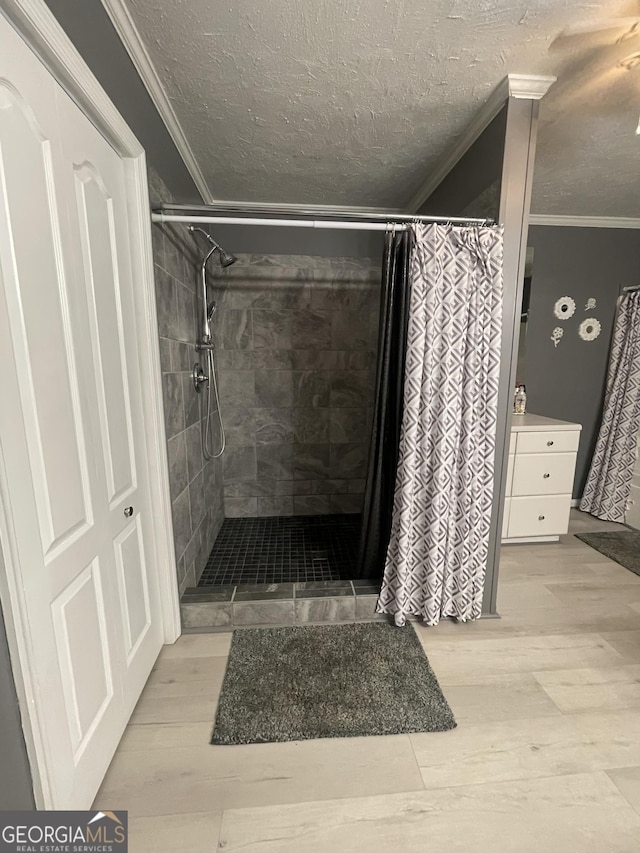 bathroom with a shower stall, wood finished floors, a textured ceiling, and ornamental molding
