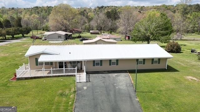 view of front of house featuring a front lawn, driveway, and metal roof