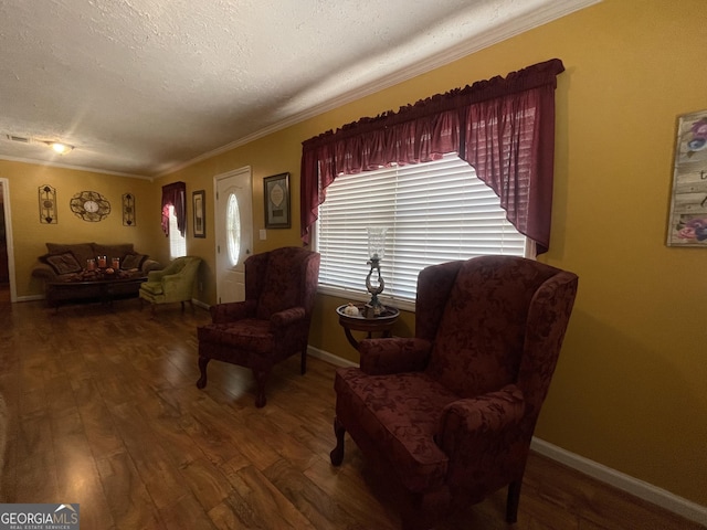 sitting room featuring baseboards, ornamental molding, wood finished floors, and a textured ceiling
