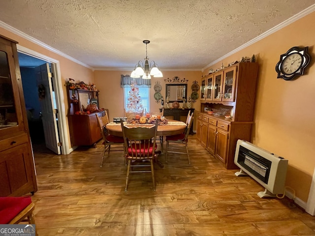dining area featuring a notable chandelier, wood finished floors, heating unit, and a textured ceiling