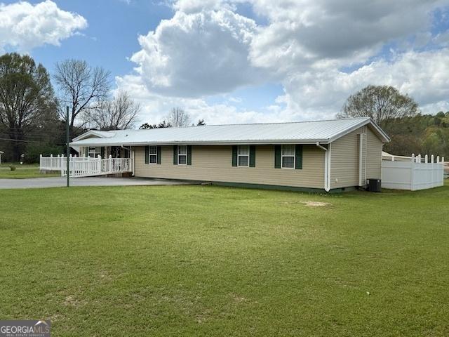 view of front of property with fence, metal roof, a front yard, and central AC unit