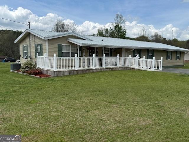 view of front of home with a front lawn, covered porch, central air condition unit, and metal roof