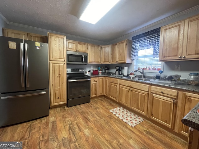 kitchen with stainless steel appliances, light wood-style flooring, light brown cabinetry, a sink, and ornamental molding
