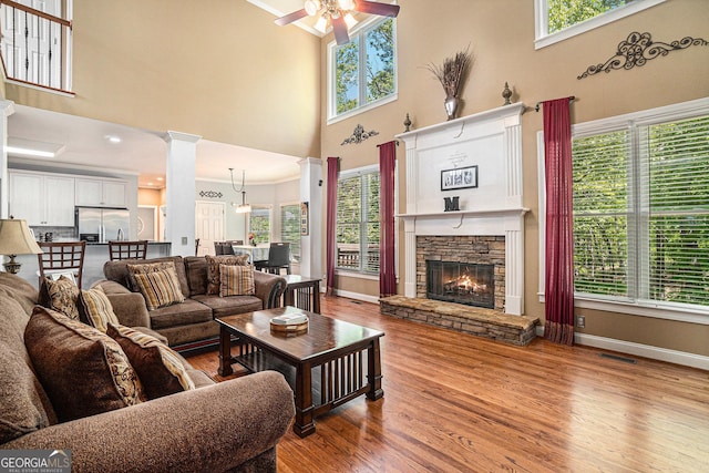 629 Gold Valley Pass, Canton, GA 30114 - living room featuring plenty of natural light, a ceiling fan, a stone fireplace, a towering ceiling, and wood finished floors