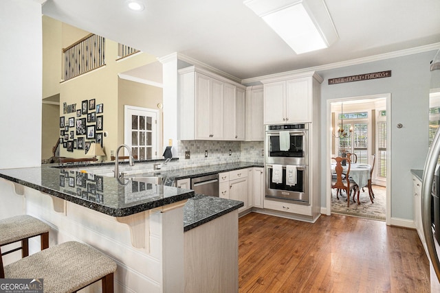 629 Gold Valley Pass, Canton, GA 30114 - kitchen with a kitchen breakfast bar, appliances with stainless steel finishes, a peninsula, ornamental molding, and dark wood-type flooring