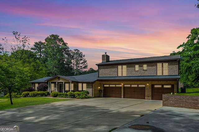 view of front of house with driveway, a garage, a chimney, and a front yard