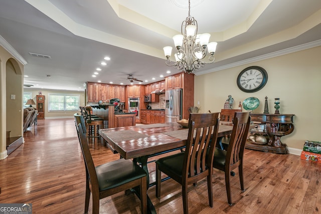 dining room with a chandelier, recessed lighting, a tray ceiling, wood finished floors, and ceiling fan