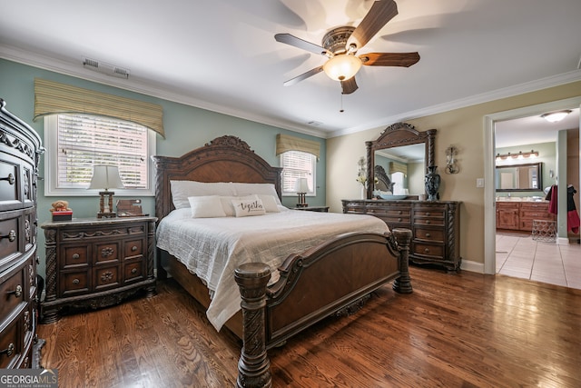 bedroom with wood finished floors, crown molding, ensuite bath, and a ceiling fan