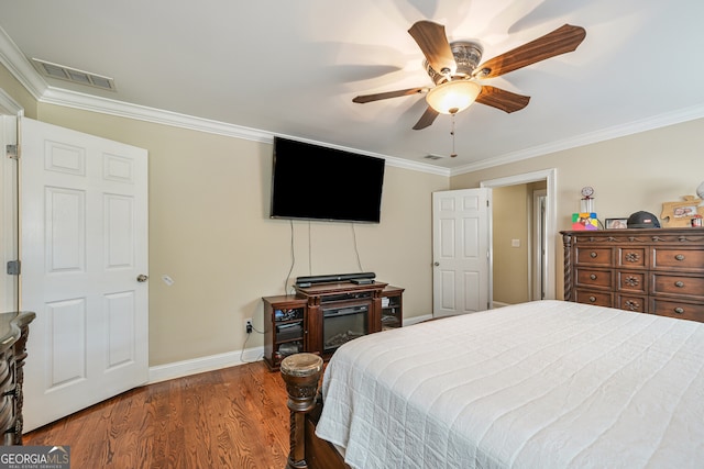 bedroom with crown molding, baseboards, dark wood-style floors, and ceiling fan