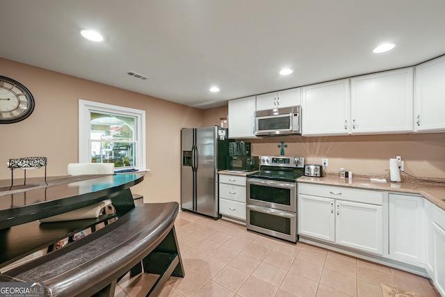 kitchen featuring appliances with stainless steel finishes, white cabinetry, light tile patterned floors, recessed lighting, and light stone counters