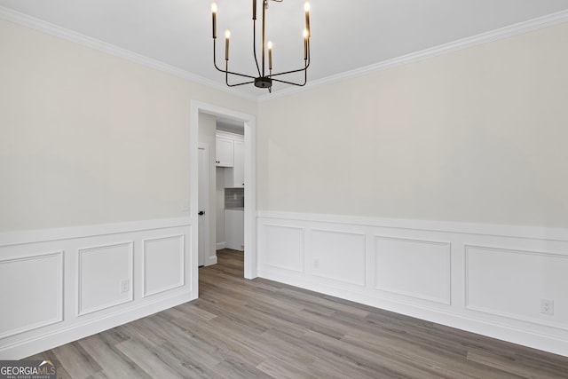130 Rudders Xing, Newnan, GA 30263 - unfurnished dining area with wainscoting, wood finished floors, an inviting chandelier, and crown molding
