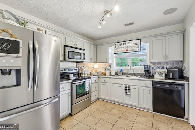 122 Eagle View Dr, Monticello, GA 31064 - kitchen with appliances with stainless steel finishes, a sink, light tile patterned floors, decorative backsplash, and a textured ceiling