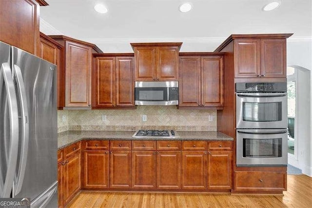 kitchen featuring double oven, a sink, light wood-type flooring, a notable chandelier, and crown molding