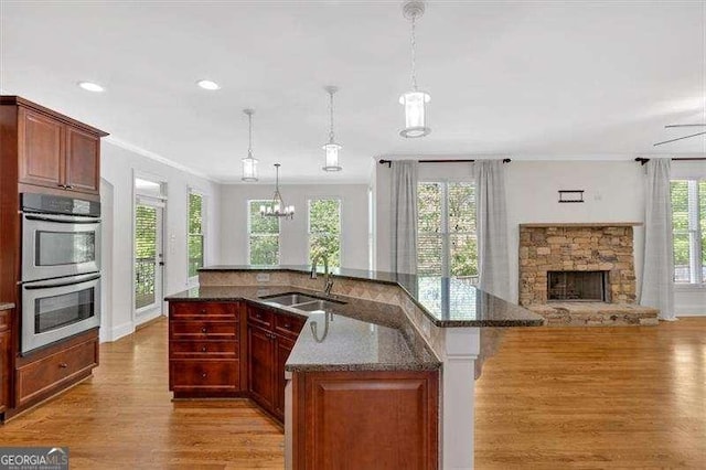 living room featuring wood finished floors, ornamental molding, ceiling fan, a fireplace, and baseboards