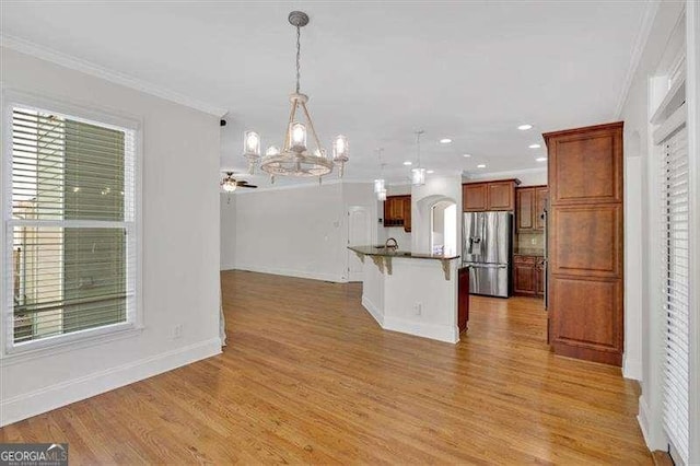 unfurnished living room featuring arched walkways, built in features, carpet, a ceiling fan, and a stone fireplace