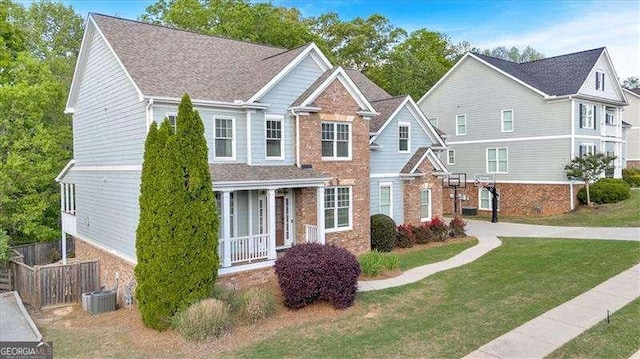 view of front facade featuring brick siding, fence, driveway, a front yard, and an attached garage