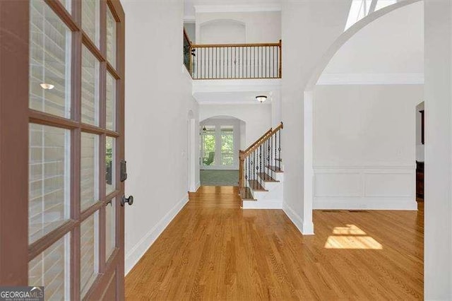 foyer entrance featuring wood finished floors, a healthy amount of sunlight, and arched walkways