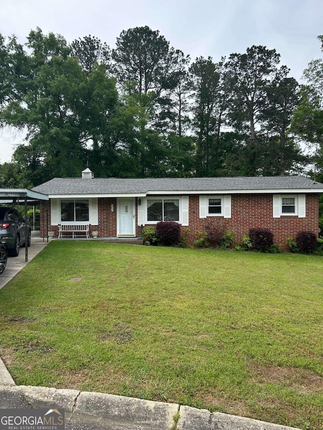 ranch-style home featuring brick siding, a front lawn, and a carport