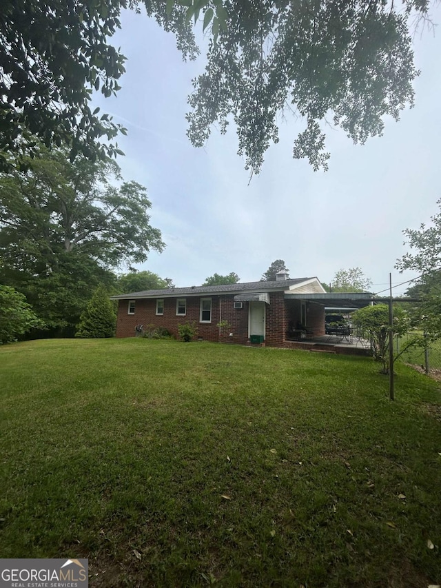 exterior space with brick siding, a front lawn, and a carport