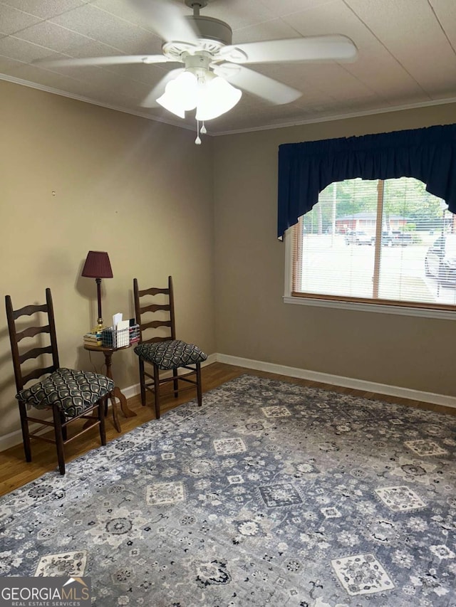 sitting room with ceiling fan, baseboards, ornamental molding, and wood finished floors