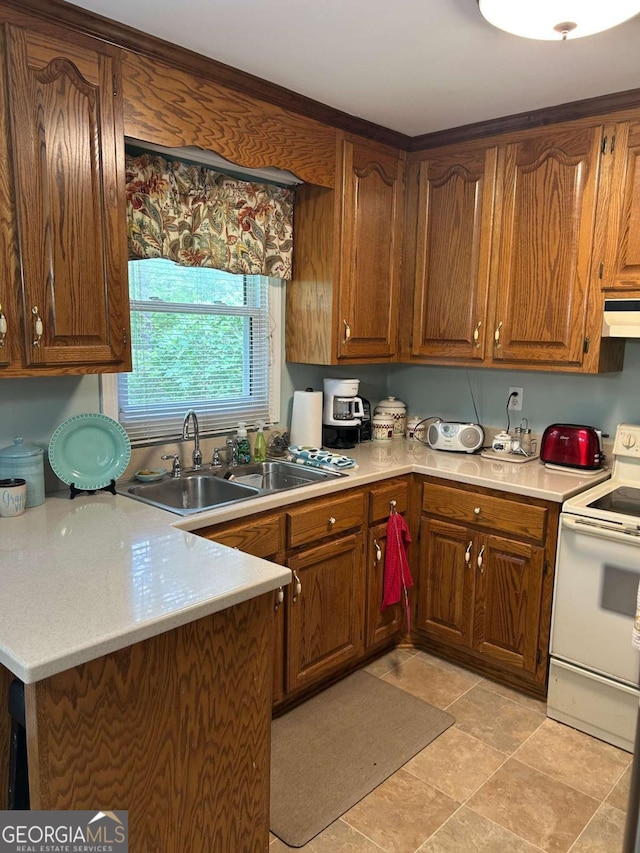 kitchen featuring under cabinet range hood, light countertops, electric stove, a sink, and brown cabinetry