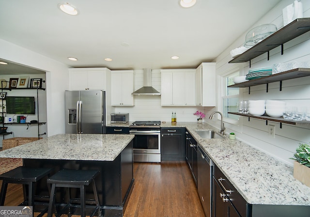 1907 Shalimar Dr NE, Atlanta, GA 30345 - kitchen featuring appliances with stainless steel finishes, wall chimney range hood, light stone counters, white cabinetry, and a center island