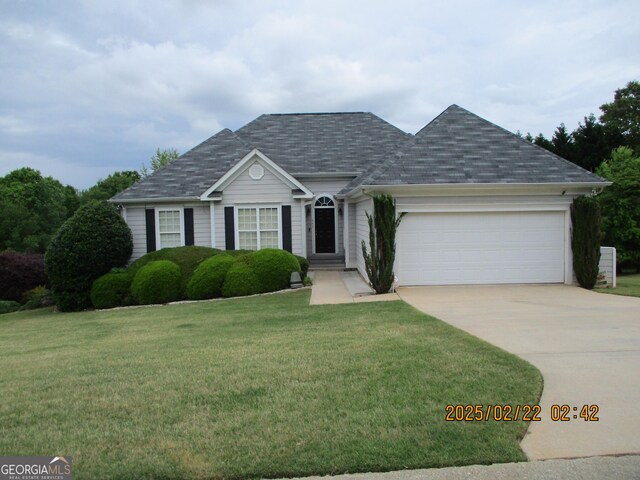 ranch-style home featuring concrete driveway, an attached garage, a shingled roof, and a front lawn